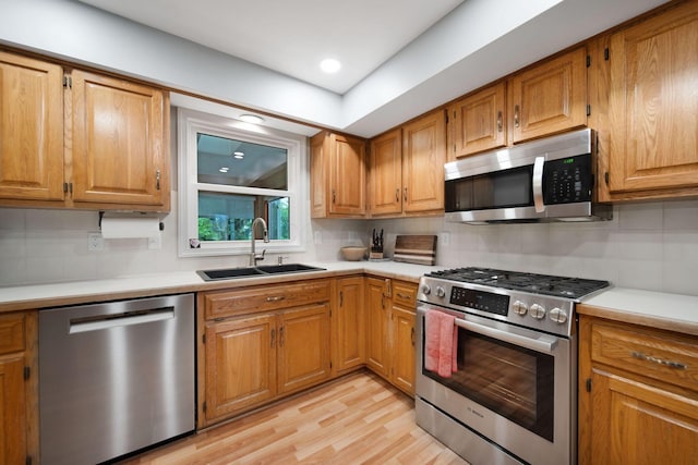 1055 Arcaro Dr, Columbus, OH 43230 - kitchen with stainless steel appliances, a sink, backsplash, light wood-style floors, and light countertops