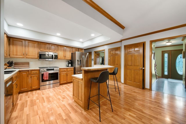1055 Arcaro Dr, Columbus, OH 43230 - kitchen featuring stainless steel appliances, crown molding, light countertops, a kitchen island, and light wood-type flooring