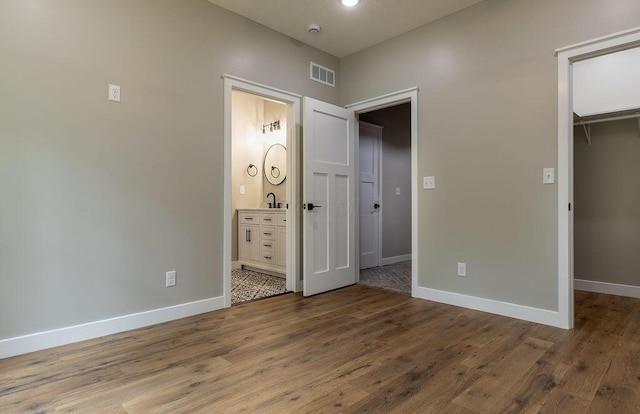 21650 Lake Rd, Glouster, OH 45732 - unfurnished bedroom featuring a walk in closet, baseboards, a closet, wood finished floors, and ensuite bath