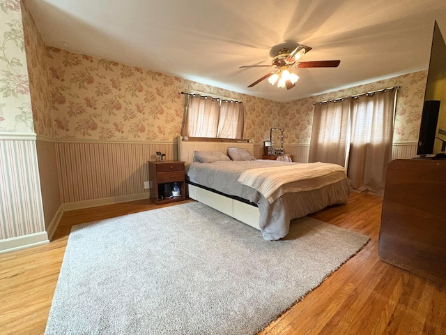 2010 S Main St, Findlay, OH 45840 - bedroom featuring wallpapered walls, a wainscoted wall, wood finished floors, and a ceiling fan