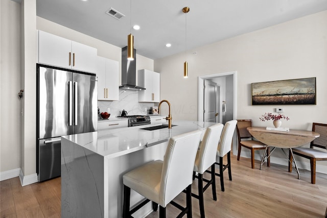 6640 Mooney St Unit 402, Dublin, OH 43017 - kitchen featuring appliances with stainless steel finishes, wall chimney range hood, a sink, light wood-style flooring, and backsplash