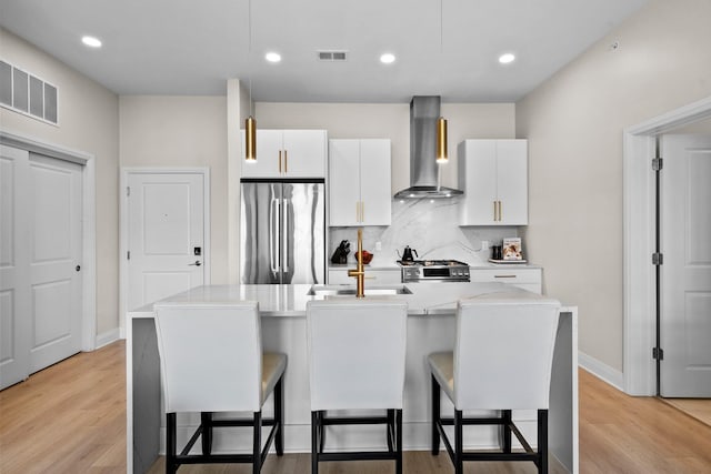 6640 Mooney St Unit 402, Dublin, OH 43017 - kitchen featuring stainless steel fridge, wall chimney range hood, a breakfast bar area, white cabinetry, and recessed lighting