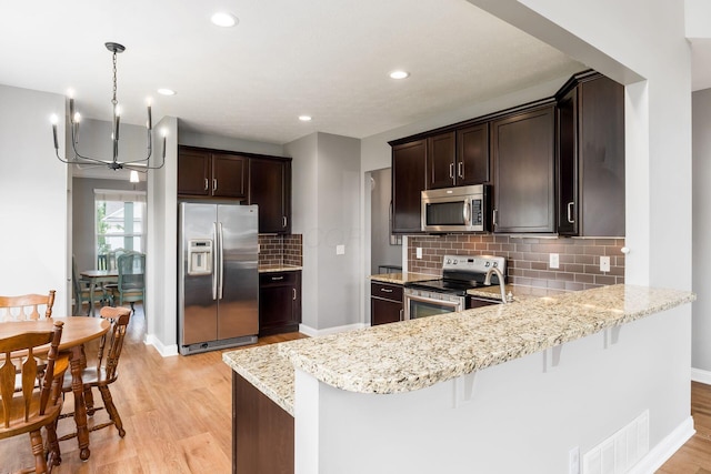 6458 Tallman Ct, Canal Winchester, OH 43110 - kitchen with appliances with stainless steel finishes, light stone counters, a peninsula, a chandelier, and recessed lighting