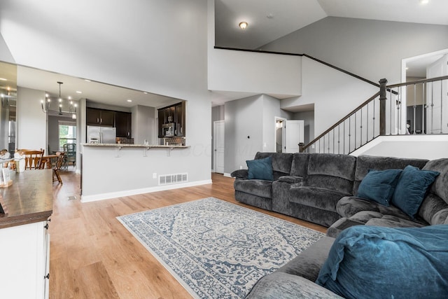 6458 Tallman Ct, Canal Winchester, OH 43110 - living room featuring high vaulted ceiling, a chandelier, light wood finished floors, and stairway