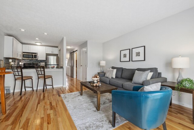 1994 Hoadley Dr Unit 7C, Columbus, OH 43228 - living area featuring light wood-type flooring, a barn door, recessed lighting, baseboards, and a textured ceiling