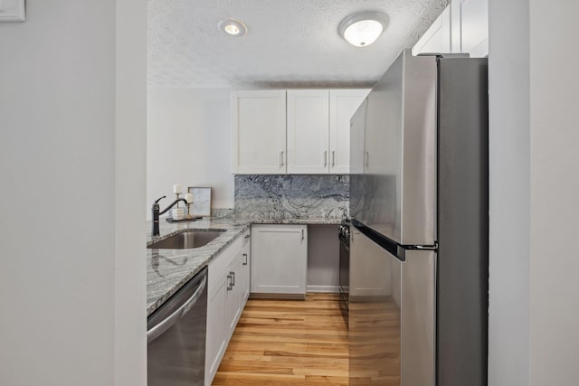 1994 Hoadley Dr Unit 7C, Columbus, OH 43228 - kitchen with appliances with stainless steel finishes, a sink, a textured ceiling, light wood-style floors, and white cabinetry