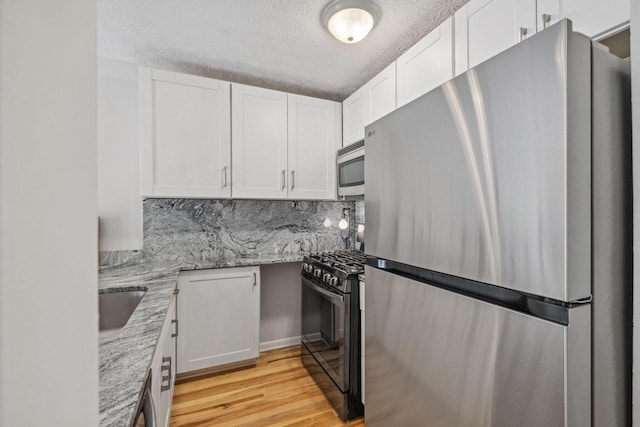 1994 Hoadley Dr Unit 7C, Columbus, OH 43228 - kitchen featuring appliances with stainless steel finishes, white cabinetry, light wood-style flooring, light stone counters, and a textured ceiling