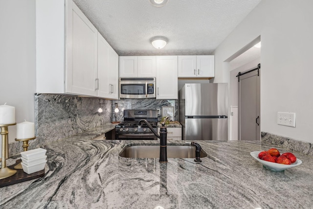 1994 Hoadley Dr Unit 7C, Columbus, OH 43228 - kitchen featuring appliances with stainless steel finishes, light stone countertops, a barn door, white cabinetry, and a textured ceiling
