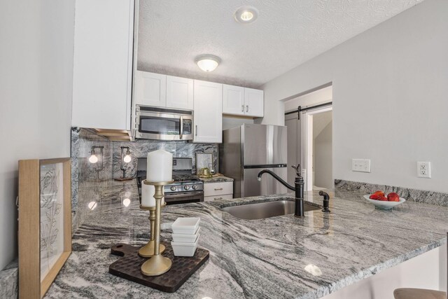 1994 Hoadley Dr Unit 7C, Columbus, OH 43228 - kitchen with stainless steel appliances, a peninsula, a sink, white cabinets, and light stone countertops