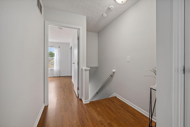 1994 Hoadley Dr Unit 7C, Columbus, OH 43228 - hall featuring an upstairs landing, wood finished floors, baseboards, and a textured ceiling