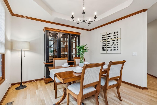 1229 Whispering Meadow Ct, New Albany, OH 43054 - dining space featuring a raised ceiling, light wood-style flooring, a chandelier, and crown molding