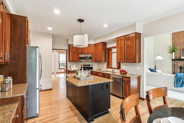 1229 Whispering Meadow Ct, New Albany, OH 43054 - kitchen featuring appliances with stainless steel finishes, light wood-style flooring, decorative backsplash, a kitchen island, and light stone countertops