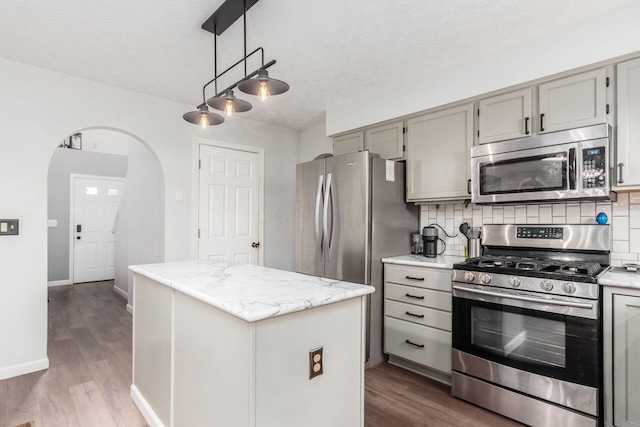 2535 Linbaugh Rd, Grove City, OH 43123 - kitchen featuring appliances with stainless steel finishes, a center island, arched walkways, gray cabinets, and dark wood-style flooring