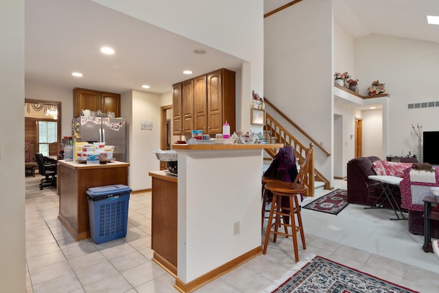 7415 Sand Spurrey Ct, Westerville, OH 43082 - kitchen featuring freestanding refrigerator, a breakfast bar, brown cabinetry, open floor plan, and a peninsula