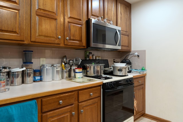 7415 Sand Spurrey Ct, Westerville, OH 43082 - kitchen with stainless steel microwave, range with gas stovetop, light countertops, tasteful backsplash, and brown cabinets
