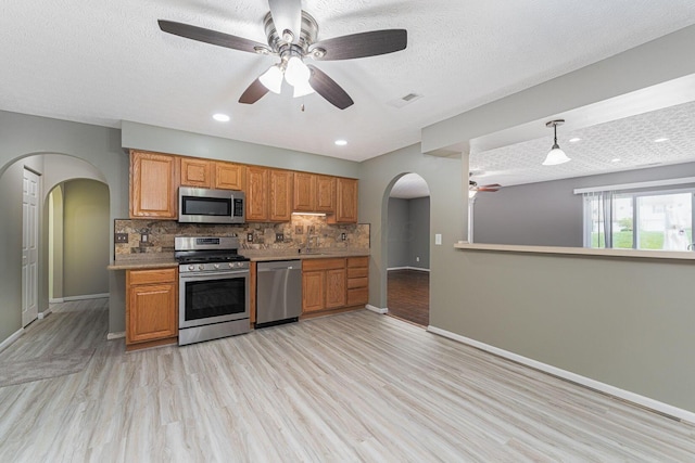 5924 Morrissey St Unit 5924E, Columbus, OH 43232 - kitchen with appliances with stainless steel finishes, ceiling fan, arched walkways, light wood-style flooring, and tasteful backsplash