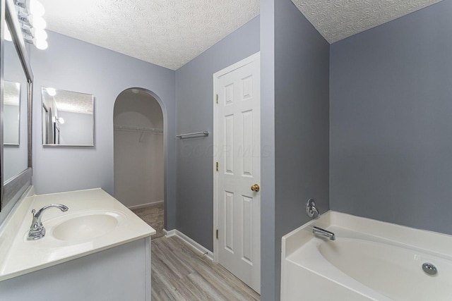 5924 Morrissey St Unit 5924E, Columbus, OH 43232 - bathroom featuring a garden tub, a textured ceiling, vanity, wood finished floors, and a walk in closet
