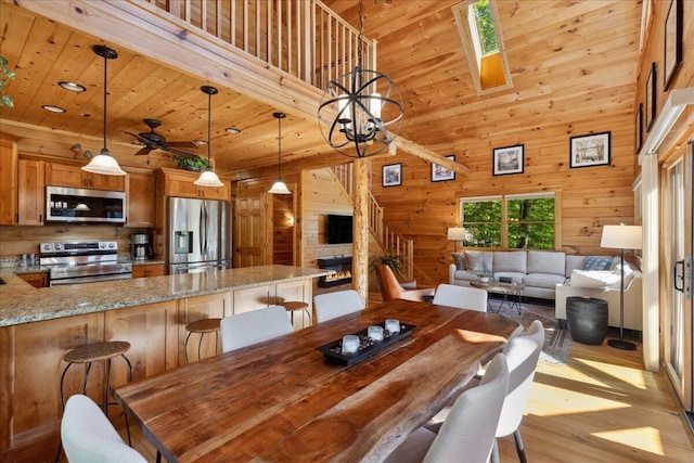 653 Natchez Ln, Sugar Grove, OH 43155 - dining space featuring light wood-style floors, wooden walls, wood ceiling, ceiling fan, and a high ceiling