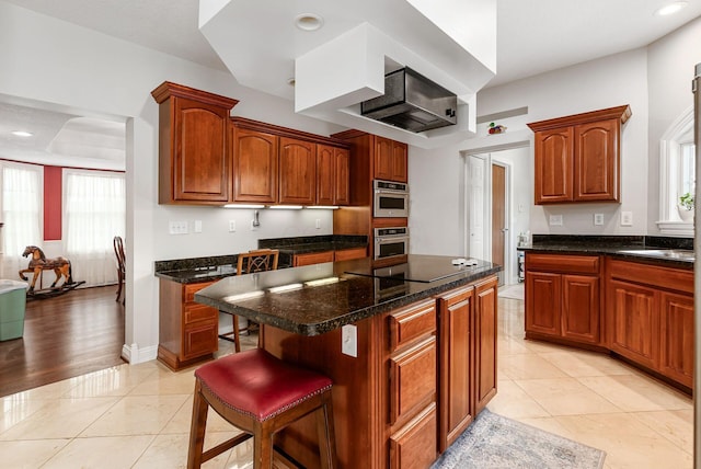 5360 Smothers Rd, Westerville, OH 43081 - kitchen with black electric stovetop, a kitchen island, a breakfast bar area, recessed lighting, and brown cabinets