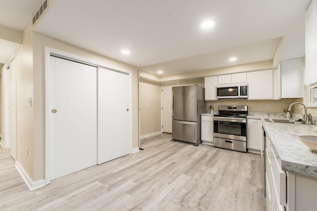1419 Hentz Dr, Reynoldsburg, OH 43068 - kitchen with stainless steel appliances, a sink, light wood-type flooring, white cabinetry, and baseboards