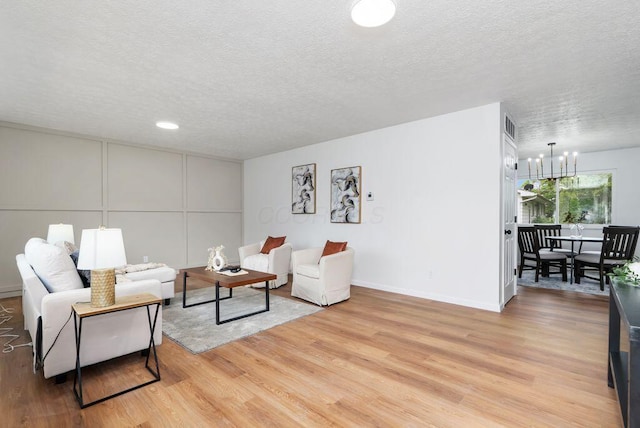 215 Stockbridge Rd, Columbus, OH 43207 - living area with a textured ceiling, light wood-style floors, baseboards, a chandelier, and a decorative wall