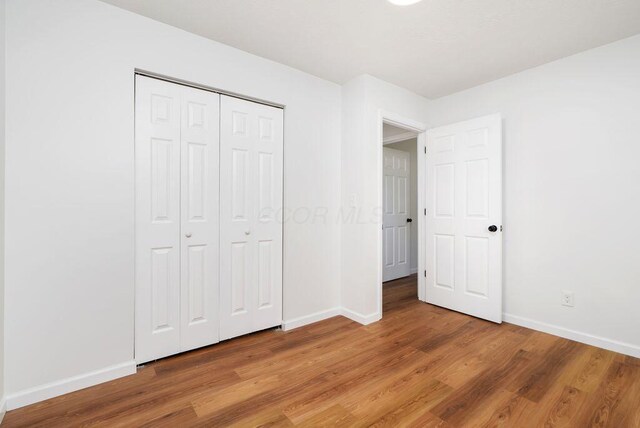215 Stockbridge Rd, Columbus, OH 43207 - unfurnished bedroom featuring baseboards, light wood finished floors, and a closet