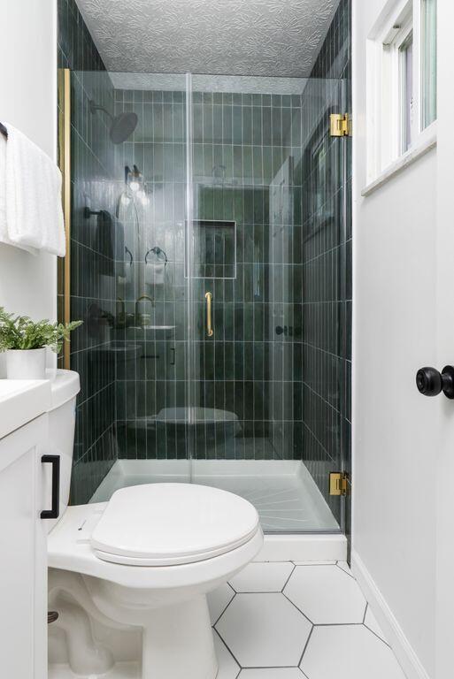 215 Stockbridge Rd, Columbus, OH 43207 - bathroom with toilet, a stall shower, tile patterned floors, vanity, and baseboards