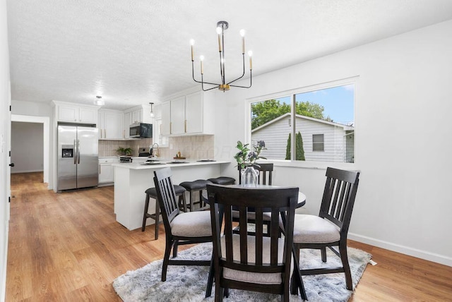 215 Stockbridge Rd, Columbus, OH 43207 - dining room featuring a chandelier, light wood-style flooring, baseboards, and a textured ceiling