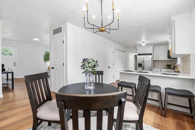 215 Stockbridge Rd, Columbus, OH 43207 - dining space with a textured ceiling, a chandelier, and light wood-type flooring