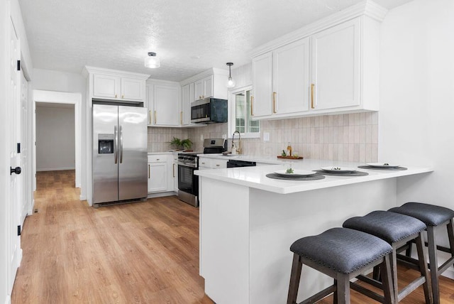 215 Stockbridge Rd, Columbus, OH 43207 - kitchen with stainless steel appliances, light countertops, a peninsula, a breakfast bar, and a textured ceiling