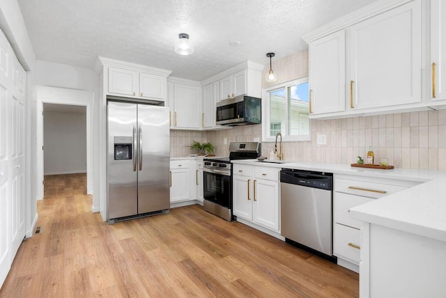215 Stockbridge Rd, Columbus, OH 43207 - kitchen featuring stainless steel appliances, a sink, white cabinetry, light countertops, and a textured ceiling