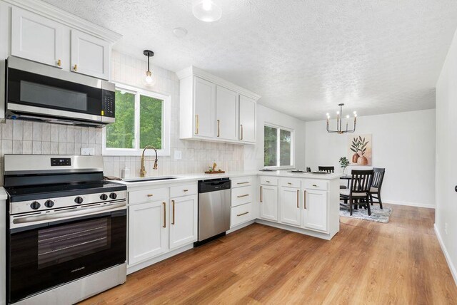 215 Stockbridge Rd, Columbus, OH 43207 - kitchen with appliances with stainless steel finishes, a sink, a chandelier, light countertops, and white cabinetry