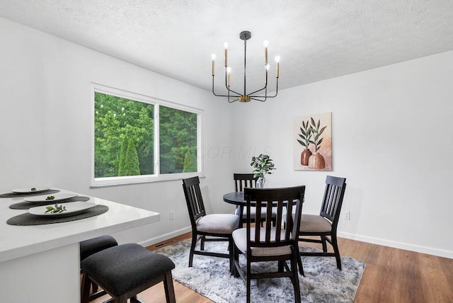 215 Stockbridge Rd, Columbus, OH 43207 - dining room with a chandelier, baseboards, light wood finished floors, and a textured ceiling