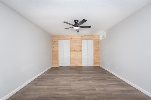26 Crabtree Ct, Howard, OH 43028 - unfurnished bedroom featuring connected bathroom, baseboards, wood finished floors, wood walls, and a ceiling fan