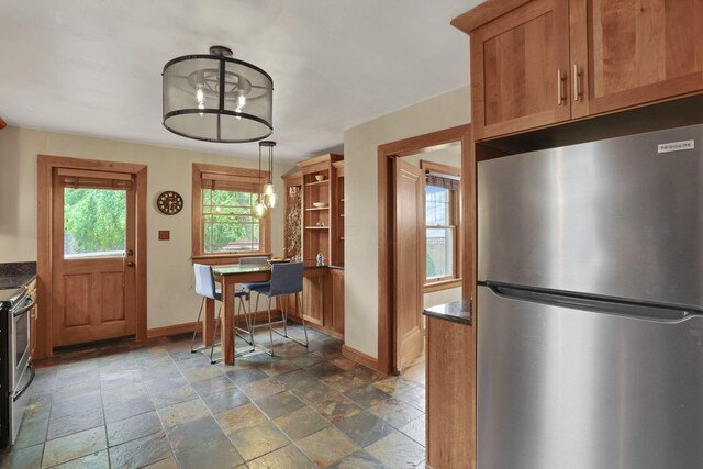 249 Blenheim Rd, Columbus, OH 43214 - kitchen featuring stainless steel appliances, stone tile flooring, baseboards, and brown cabinetry