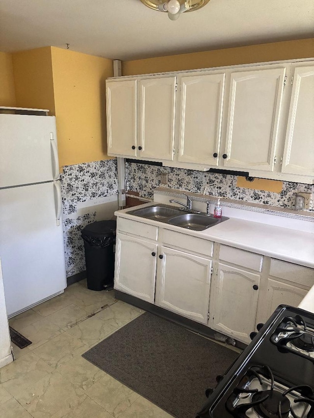909 Stephen Dr W, Columbus, OH 43204 - kitchen with freestanding refrigerator, a sink, white cabinetry, gas stove, and light countertops