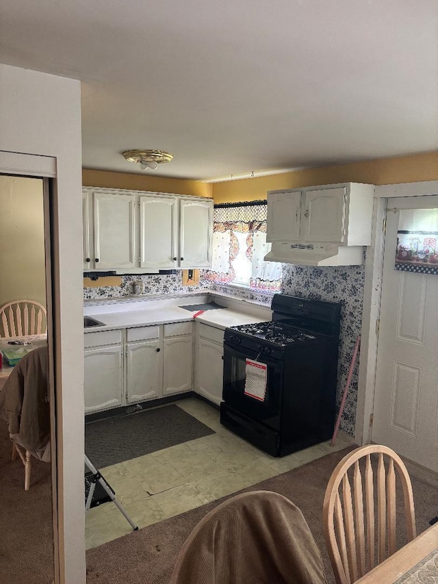 909 Stephen Dr W, Columbus, OH 43204 - kitchen featuring black range with gas stovetop, under cabinet range hood, light countertops, and white cabinets