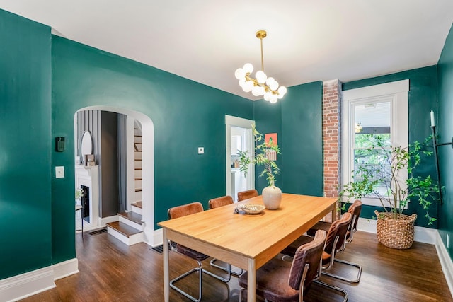 976 Oakwood Ave, Columbus, OH 43206 - dining space featuring dark wood-style floors, arched walkways, baseboards, a chandelier, and stairway