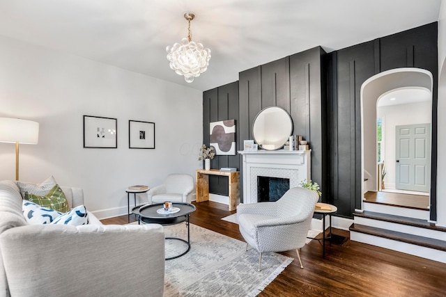 976 Oakwood Ave, Columbus, OH 43206 - living room with dark wood-style floors, a tile fireplace, arched walkways, baseboards, and a chandelier