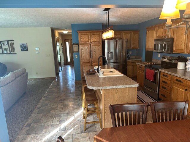 350 S Houston Pike, South Vienna, OH 45369 - kitchen featuring stainless steel appliances, a sink, an island with sink, a textured ceiling, and stone tile floors