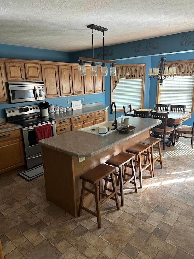 350 S Houston Pike, South Vienna, OH 45369 - kitchen featuring stainless steel appliances, a kitchen breakfast bar, a textured ceiling, a sink, and a center island with sink