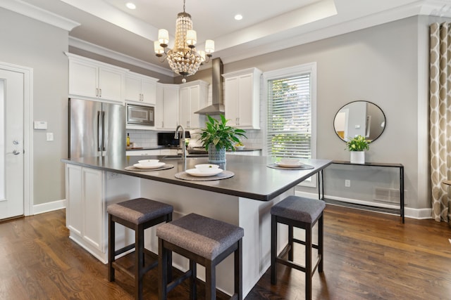 48 E 4th Ave, Columbus, OH 43201 - kitchen featuring stainless steel appliances, wall chimney exhaust hood, dark countertops, a raised ceiling, and tasteful backsplash