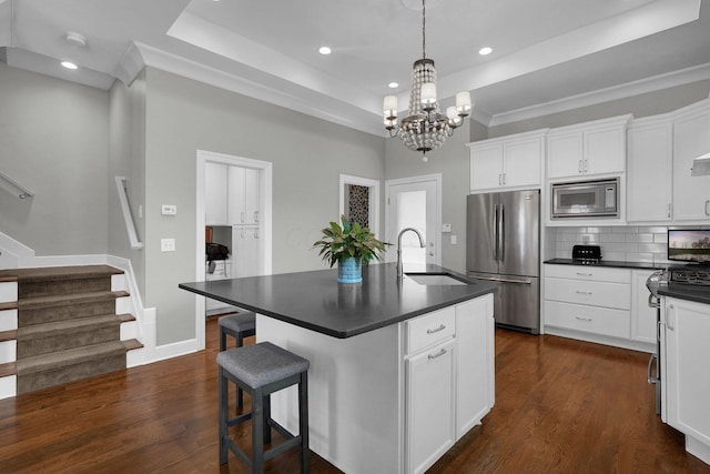 48 E 4th Ave, Columbus, OH 43201 - kitchen featuring stainless steel appliances, a sink, a tray ceiling, dark countertops, and a chandelier