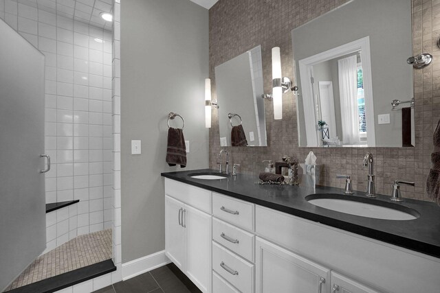 48 E 4th Ave, Columbus, OH 43201 - bathroom featuring a tile shower, double vanity, baseboards, and decorative backsplash