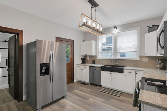 683 E 2nd St, Chillicothe, OH 45601 - kitchen with stainless steel appliances, a sink, white cabinetry, light wood-type flooring, and decorative light fixtures