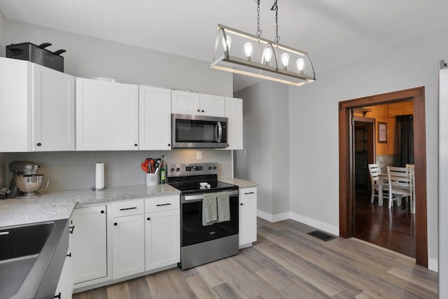 683 E 2nd St, Chillicothe, OH 45601 - kitchen with stainless steel appliances, light wood finished floors, and white cabinetry
