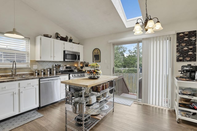 7400 Olympic Club Ct, Pickerington, OH 43147 - kitchen featuring appliances with stainless steel finishes, a sink, vaulted ceiling, decorative backsplash, and white cabinets