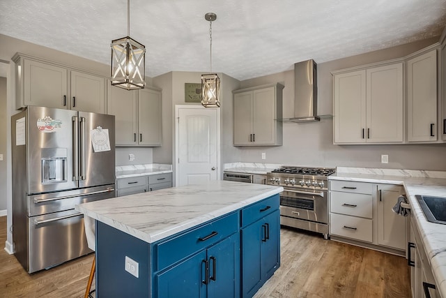 4483 County Road 124, Cardington, OH 43315 - kitchen with appliances with stainless steel finishes, wall chimney exhaust hood, light wood finished floors, a kitchen island, and blue cabinetry