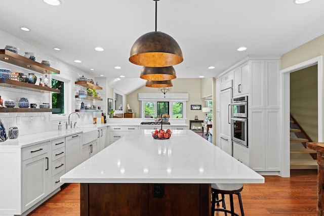 5518 Aryshire Ct, Dublin, OH 43017 - kitchen featuring open shelves, wood finished floors, white cabinetry, a peninsula, and a kitchen breakfast bar