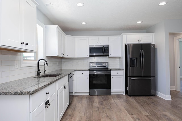 1674 Brock Rd NE, Bloomingburg, OH 43106 - kitchen featuring appliances with stainless steel finishes, a sink, white cabinets, light stone counters, and tasteful backsplash